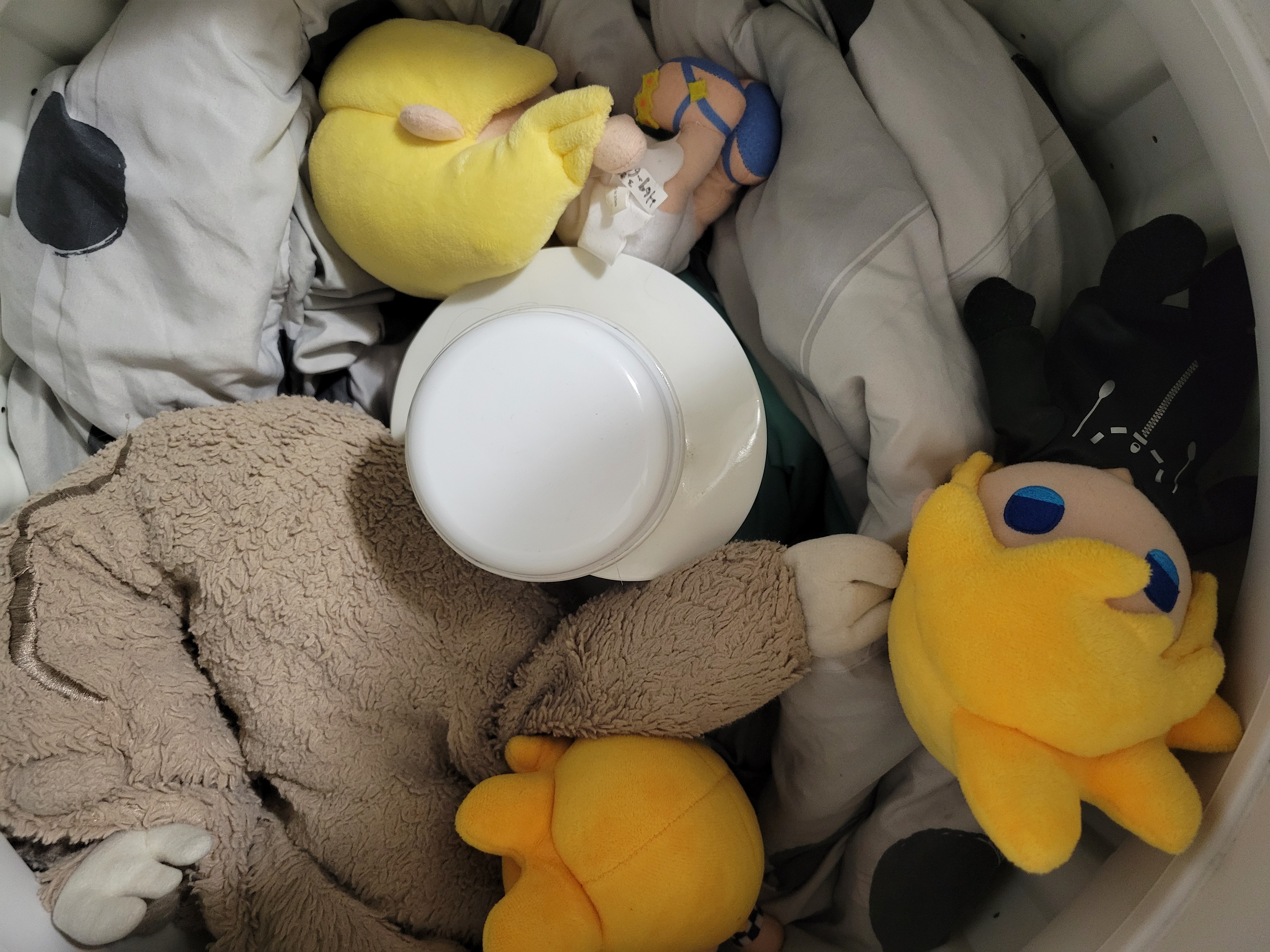 Two Kingdom Hearts Roxas, a Namine, and a sloth plush on top of a blanket in a washing machine.